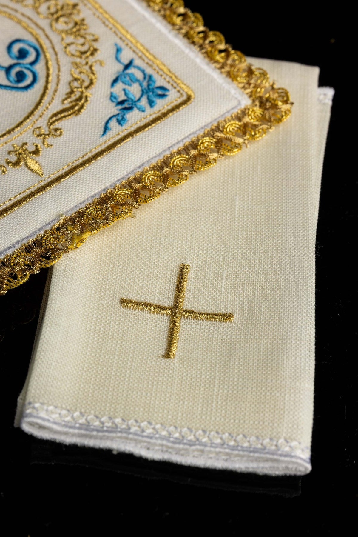 Detail view of Marian altar linens set showing a gold cross on ecru linen