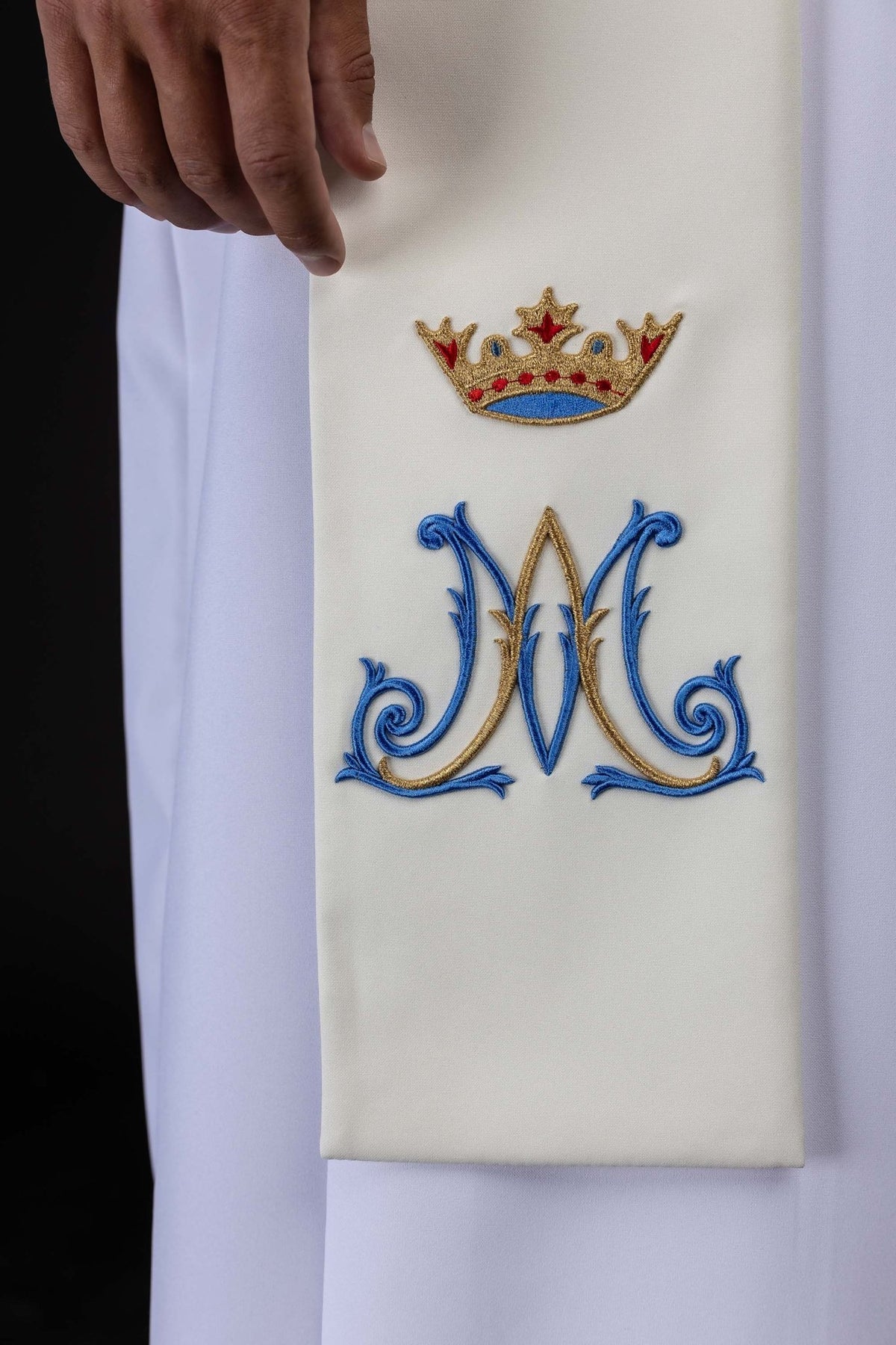 Close-up of the ecru Marian stole showing blue and gold Marian monogram embroidery