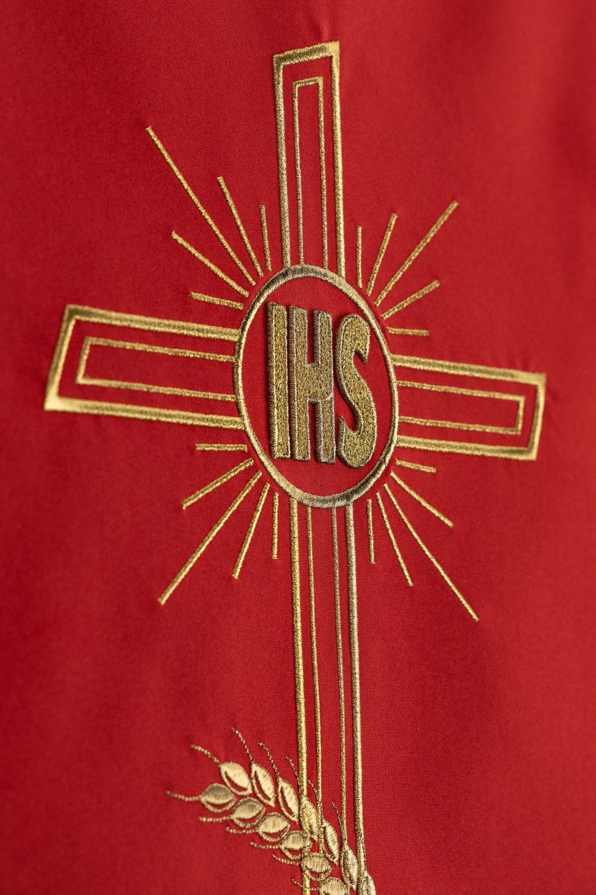 Detail view of the red lectern cloth showing the gold IHS cross and upper wheat embroidery