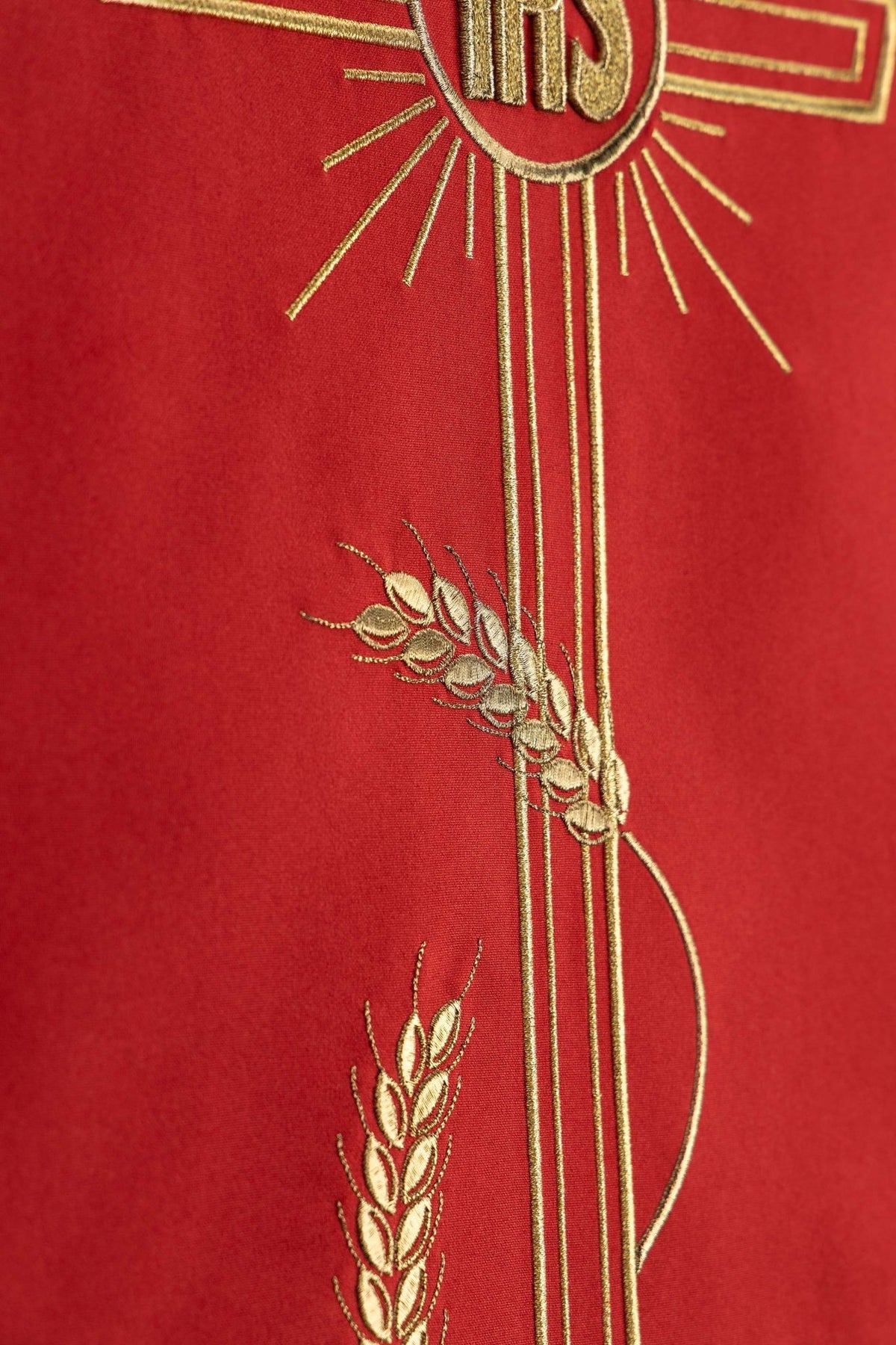 Close-up of the red lectern cloth showing gold wheat stalks beside the cross