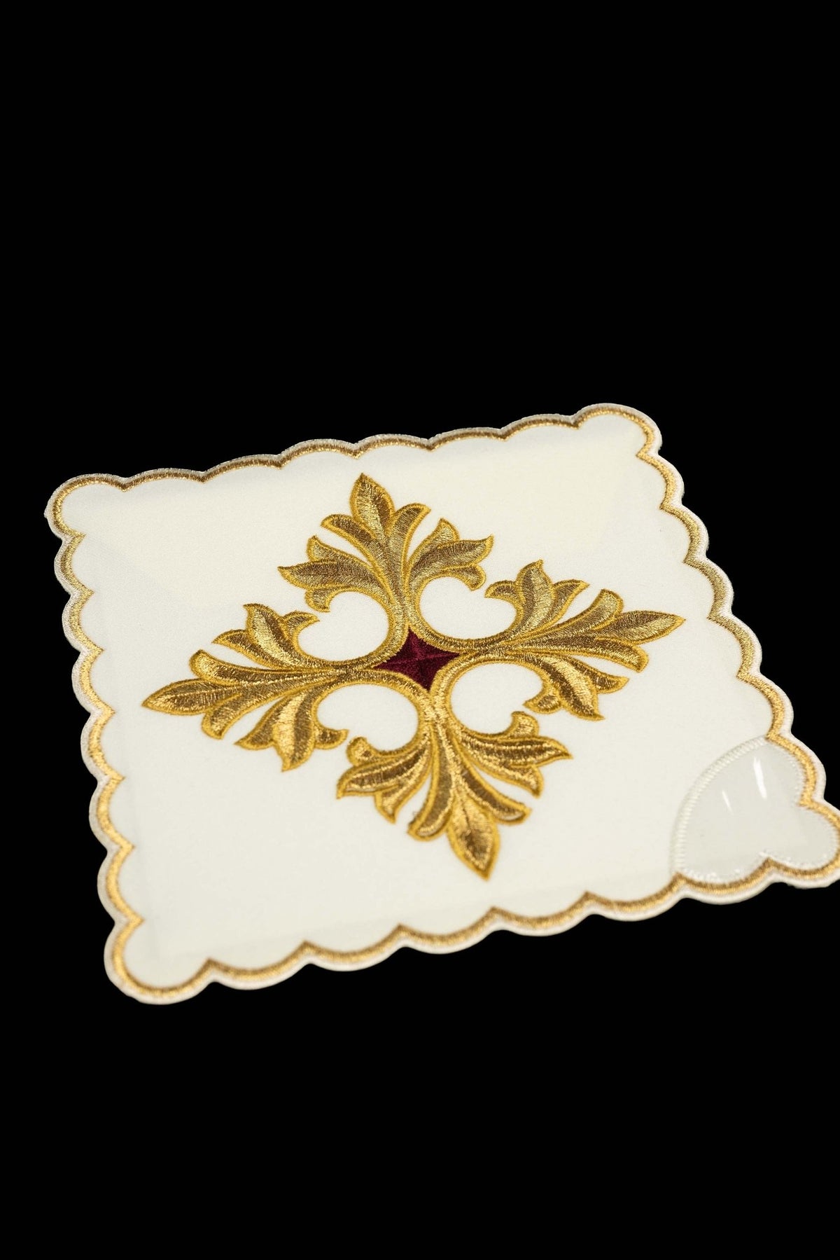 Close-up of a white chalice pall with embroidered gold cross symbol