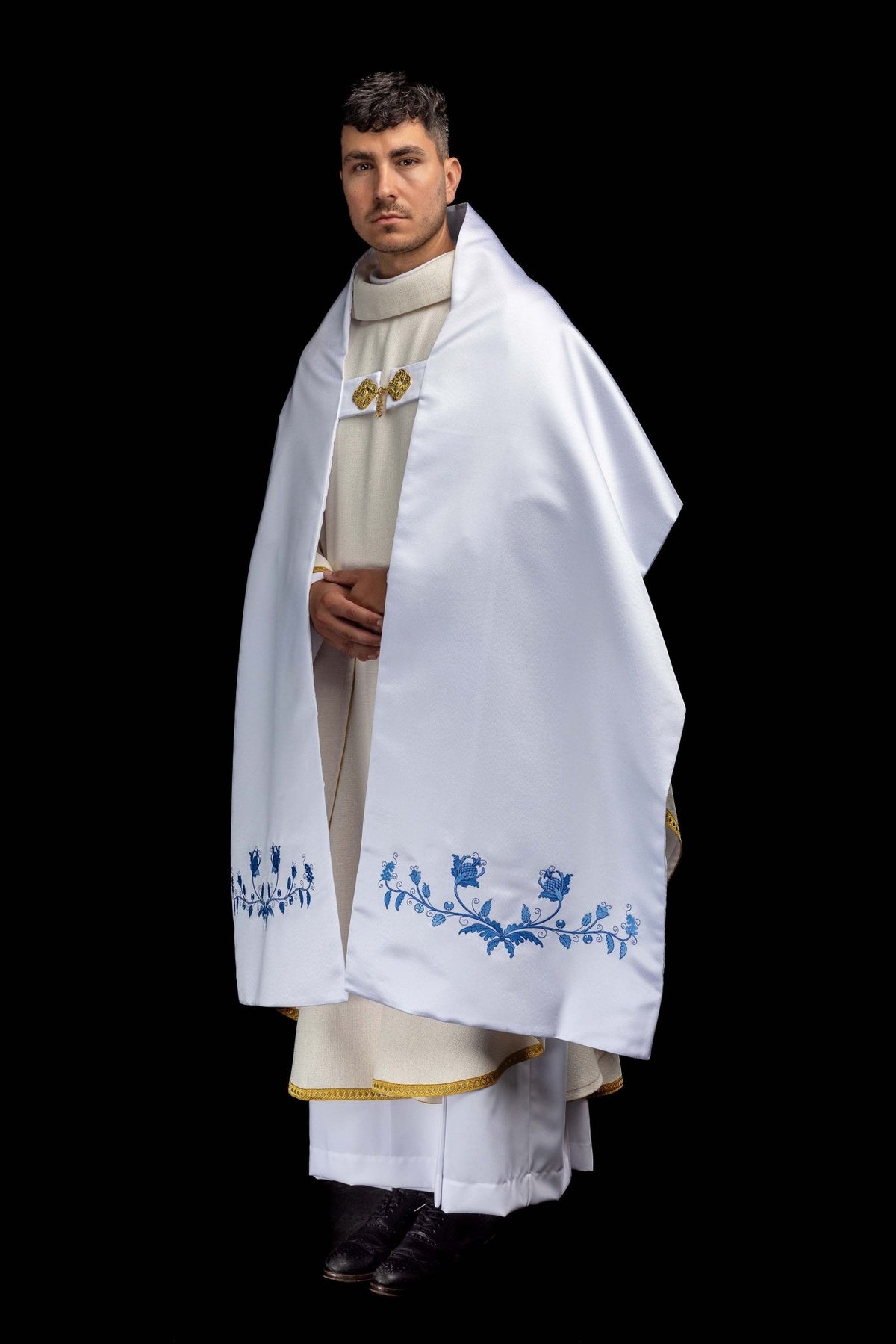Worn front view of the white humeral veil showing blue floral embroidery along both lower edges